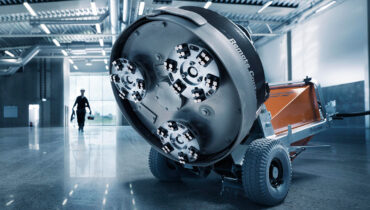 The underside of a Husqvarna concrete polisher on a shiny concrete floor in a warehouse.