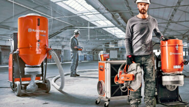 A construction worker standing inside a warehouse next to some Husqvarna dust extraction machines.