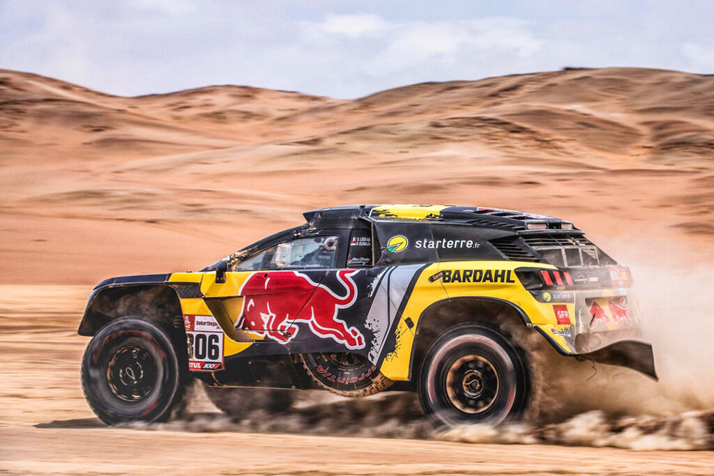 A Peugeot Dakar Rally car with Bardahl branding on the door