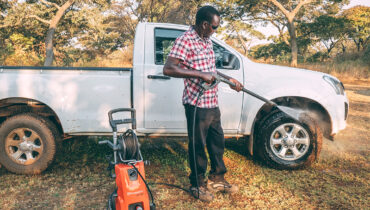 A man cleans his Isuzu single-cab with Husqvarna pressure washers.