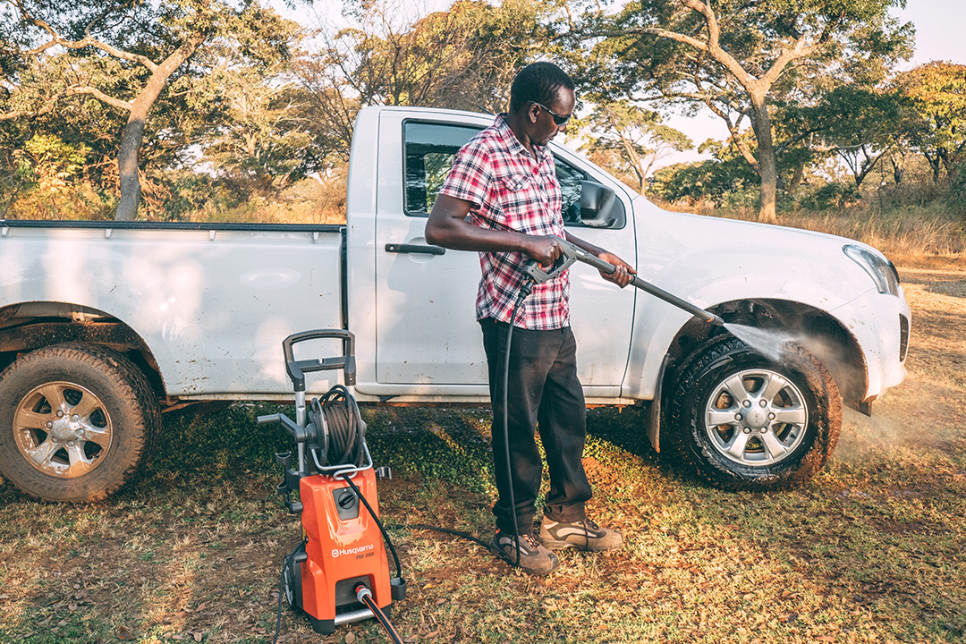 A man cleans his Isuzu single-cab with Husqvarna pressure washers.