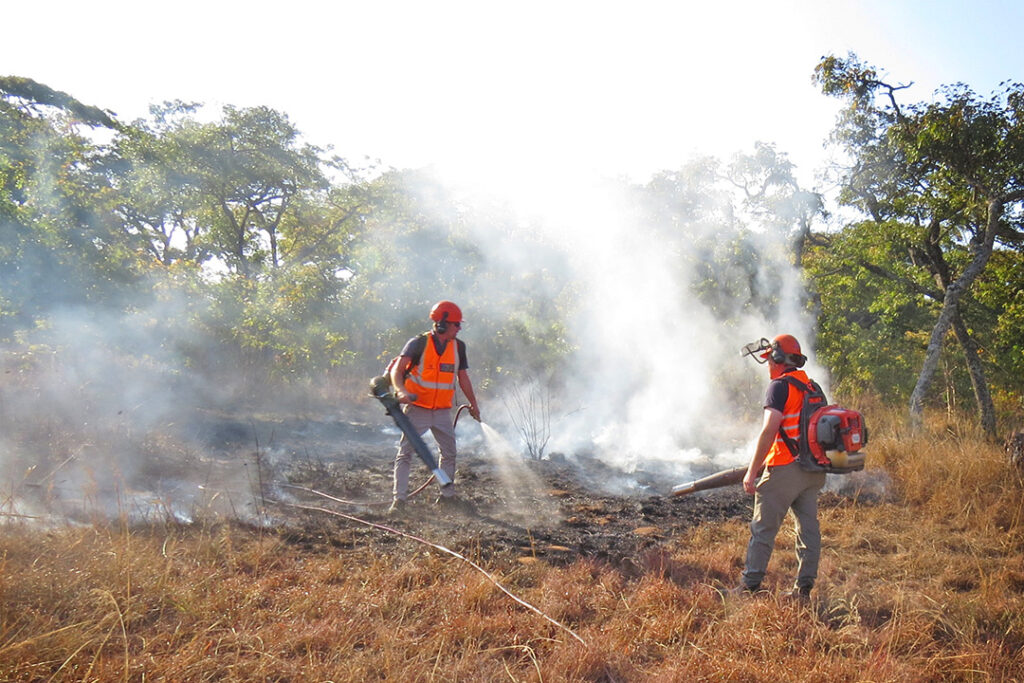 Two men extinguish a fire using Husqvarna blowers and a Hunter firefighter spray.