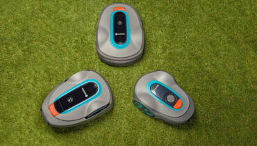 Three GARDENA robotic mowers in a triangle on a green lawn.