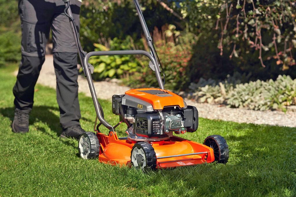 A Husqvarna LC151 petrol lawnmower on green grass.