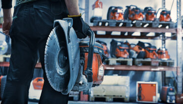 A man holding a Husqvarna power cutter inside on of the service centres.