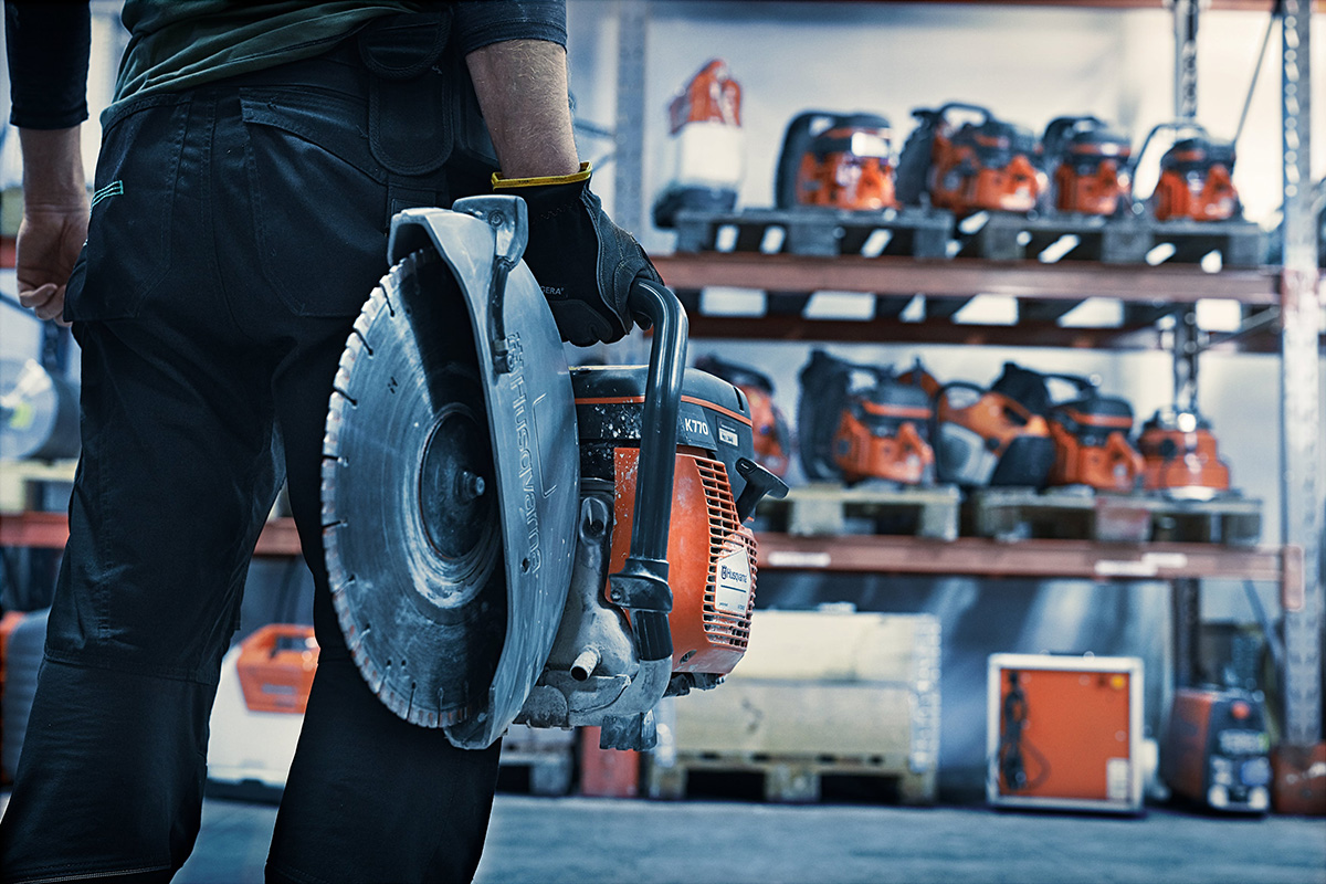 A man holding a Husqvarna power cutter inside on of the service centres.