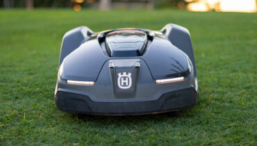 A Husqvarna 430X robotic mower on a pristine green lawn at sunset.