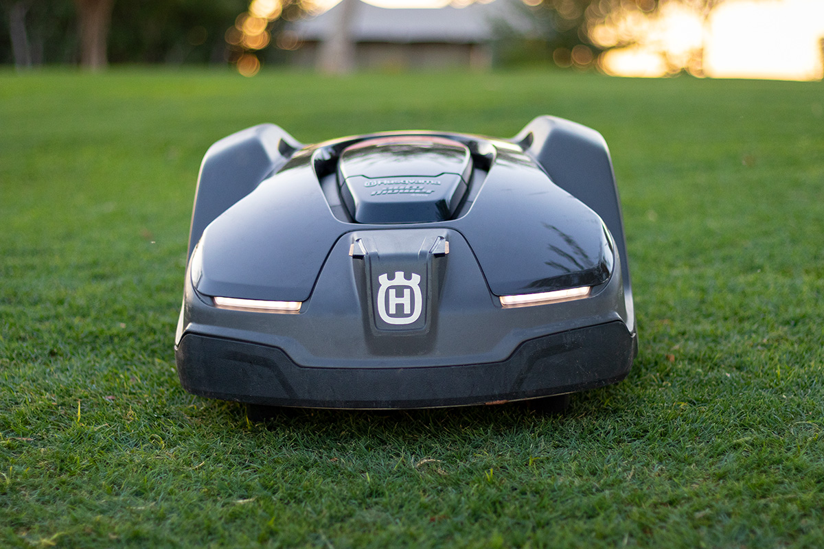 A Husqvarna 430X robotic mower on a pristine green lawn at sunset.