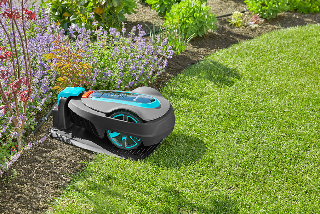 A GARDENA SILENO life 750 robotic mower charging on its docking station in a beautiful garden.